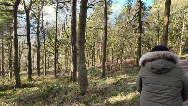 Young boy and his mother walking on a rural footpath on a day out in the forest woodlands. Countryside activity scene with moorlands winter scene