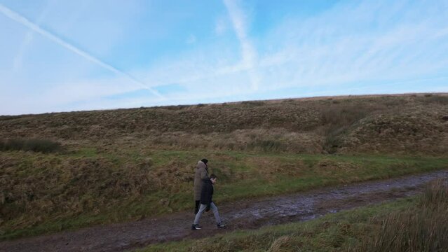 Young boy and his mother walking on a rural footpath on a day out in the country. Countryside activity scene with moorlands and a large lake