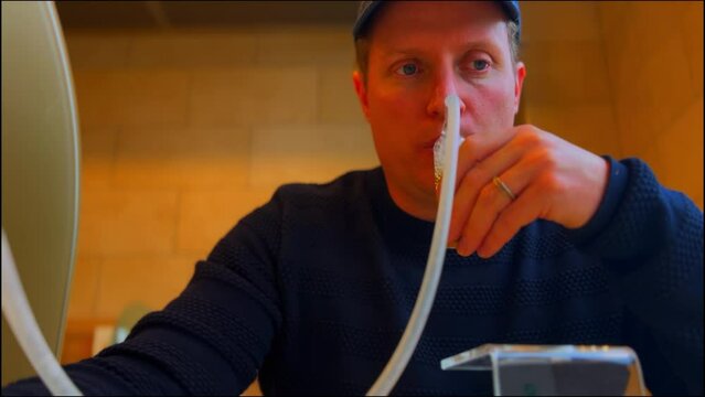 Male adult drinking tea from oxygen tube in sanatorium as anti stress treatment