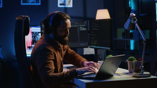 Programmer does multitasking to finish developing PC code, drinks coffee, listens music. IT admin wearing headphones, enjoying hot beverage, solving database errors on computer and laptop, camera A
