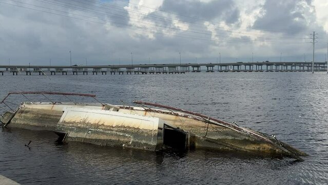 Wrecked boat in the Peace River in 2023 some distance from two (northbound and southbound) concrete bridges along U.S. Route 41 that withstood the landfalls of Hurricanes Ian and Nicole in 2022