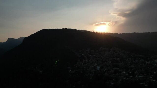 Aerial footage of the urban buildings under the green hill at sunset in Indore city, India