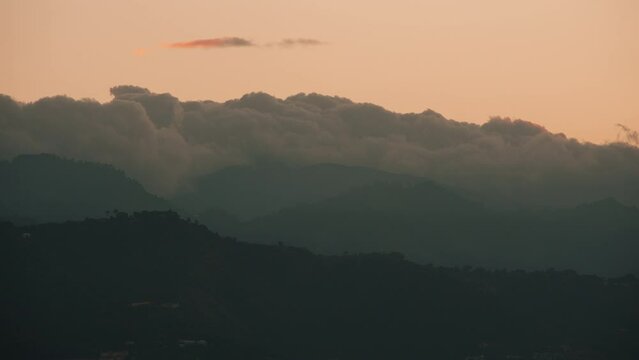 Breathtaking timelapse shot of the fog moving over the mountains at sunset in Kingston, Jamaica