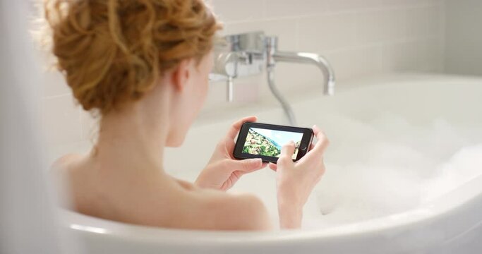 Phone, social media and woman relax in bath with bubbles, candles and self care in home. Scroll, online and person swipe with photography on smartphone in bathroom with internet, blog or website