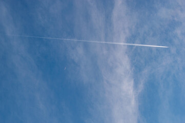 突き抜ける飛行機雲と小さな三日月