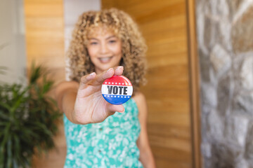 Young biracial woman holding a 'VOTE' badge, with copy space