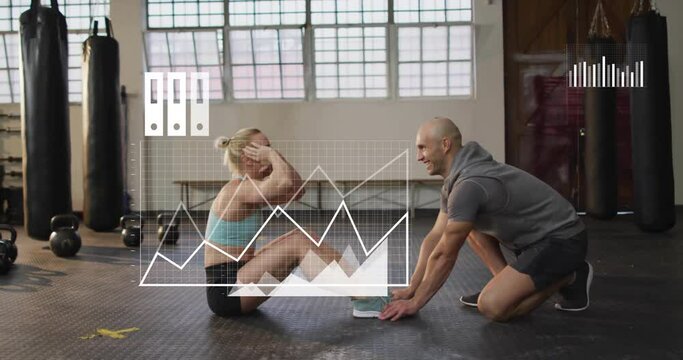 Animation of media icons and data over caucasian male instructor and woman training at gym