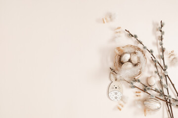 Happy Easter concept. Flat lay, top view of Easter eggs in nest, feathers, willow plant branches,...