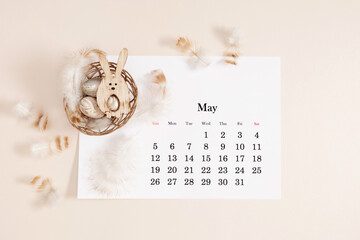 Easter concept. Flat lay, top view of paper desk calendar for May 2024 , Easter eggs, feathers in...