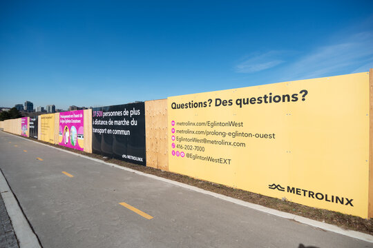 wide angle view of hoarding with billboards advertising extension of Eglinton Crosstown in Toronto, Canada