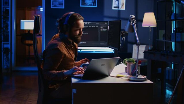 Developer typing code in home office, using Java programming language to develop software application. It professional using multimonitor PC setup and laptop to finish tasks, camera B