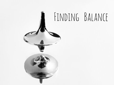 Finding balance concept. Spinning top in a mirror and text