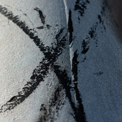 two crossing brushstrokes on a metallic surface outdoors