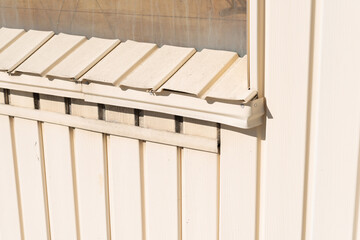 old or vintage ribbed aluminum siding painted cream in the sunlight