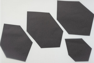 four irregular hexagonal black paper shapes on blank paper