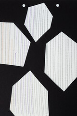 black paper frame with irregular hexagonal shape cutouts on paper with stripes