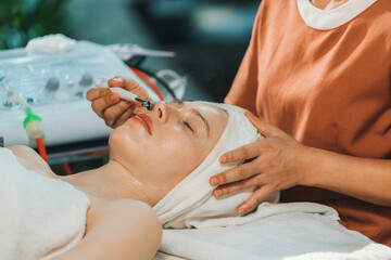 A beautiful young caucasian woman having facial massage while lies on spa bed surrounded by electrical beauty equipment. Beauty facial mask. Surrounded by medical equipment at spa salon. Tranquility.