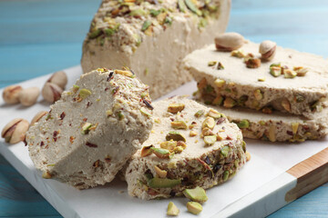 Pieces of tasty halva with pistachios on table, closeup