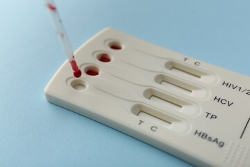 Dropping blood sample onto disposable multi-infection express test cassette with pipette on light...