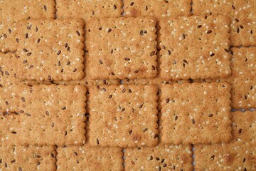 Cereal crackers with flax and sesame seeds as background, top view