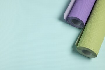 Two colorful wallpaper rolls on light turquoise sample, top view. Space for text