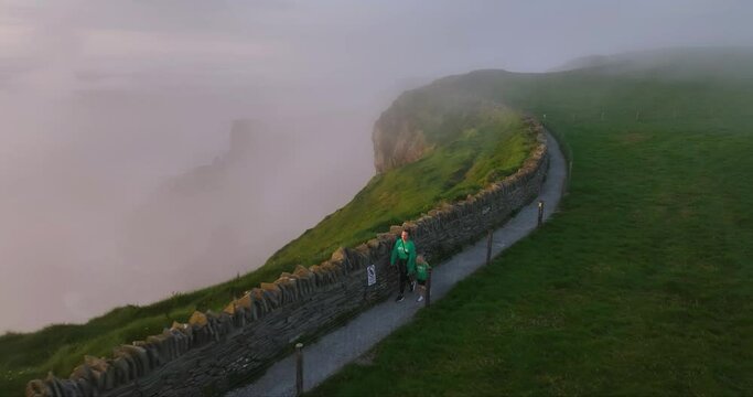 People walking on a misty trail along the Cliffs of Moher at sunset 4k