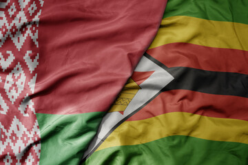 big waving national colorful flag of zimbabwe and national flag of belarus.