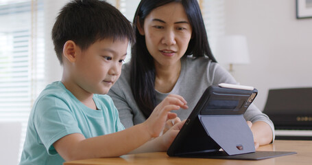 Cute asia people alpha Gen Z kid small boy play video game app online happy mum at home. Enjoy Child care fun class little son and mom study learn upskill idea course on smart digital tablet computer.