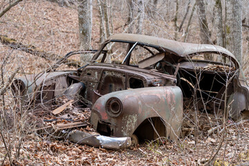 Rusted-out antique car body in the woods
