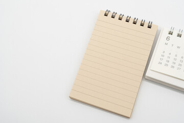 Empty Spiral notepad with brown lined papers and Simple desk calendar for JUNE in isolated background. Memo concept with copy space.