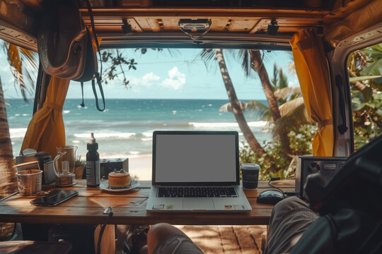 Digital Nomad concept: Closeup view of a van camper interior setting with a beautiful beach view background, focus on the laptop to evoke the idea of freedom from office and work while traveling...