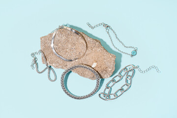 Rock with different beautiful silver bracelets on blue background