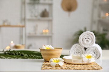 Spa composition with plumeria flowers on table in salon, closeup