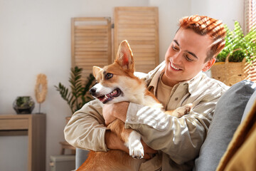 Redhead young happy man with cute Corgi dog at home