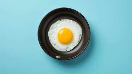 Egg yolk in blue frying pan - obrazy, fototapety, plakaty