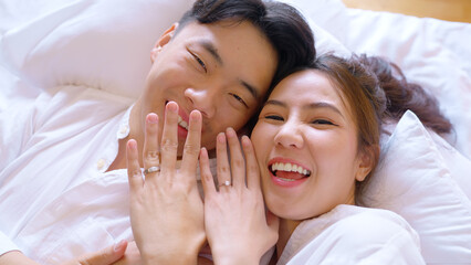 Top view young couple two asia people lying down on bed fun video phone call relax smile look at...