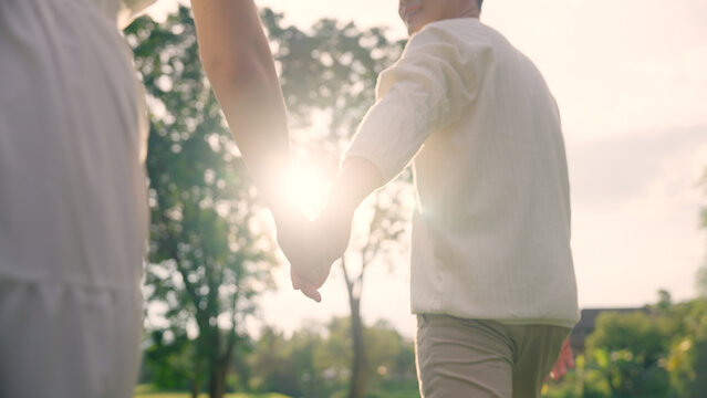 Back rear view young lover asia people happy smile trust hold hand enjoy relax walk way forward to sun light. Just married asian man woman in nature field begin family dream of life love hope and care