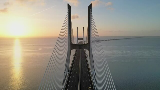 Drone flyover shot of Vasco da Gama bridge over Tagus river in Lisbon Portugal at sunset