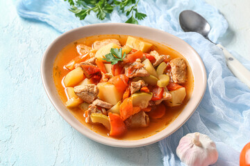 Bowl with delicious beef stew and parsley on light blue background