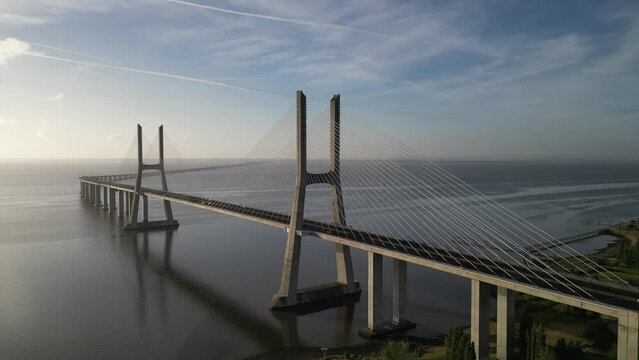Drone flyover shot of Vasco da Gama bridge over Tagus river in Lisbon, Portugal with cloudy sky