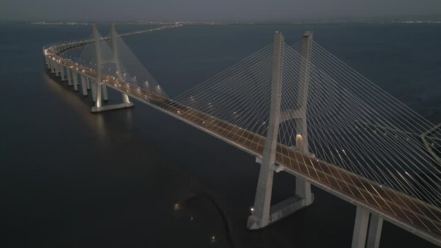 Drone flyover shot of Vasco da Gama bridge over the Tagus river in Lisbon Portugal in the evening