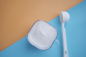 Close up of baby milk powder and spoon on tile background.