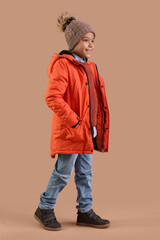 Cute African-American boy in warm clothes on brown background © Pixel-Shot