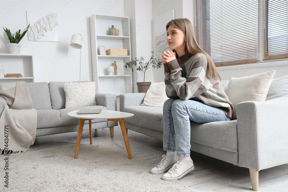 Canvas Prints young woman praying on sofa at home