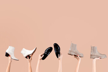 Female hands holding different boots on beige background