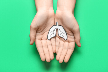 Female hands with paper lungs on green background