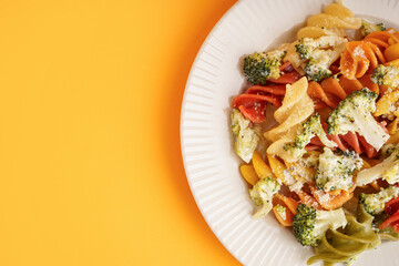 Delicious fusilli pasta with broccoli and cheese in plate on orange background