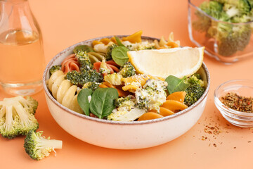 Delicious fusilli pasta with broccoli in bowl and spices on beige background, closeup