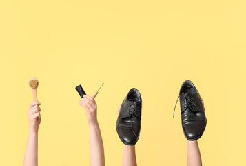 Female hands with shoes, brush and craft tools on yellow background. Shoe repair concept