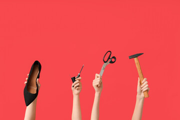 Female hands with shoe, hammer and craft tools on red background. Shoes repair concept
